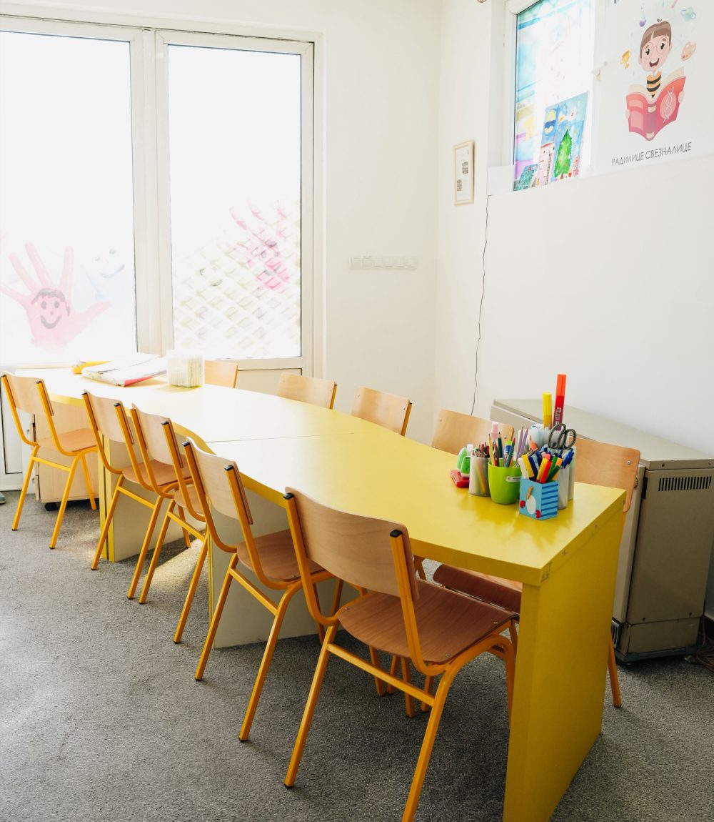Sala za radionice sa dugim žutim stolom, stolicama i bojicama